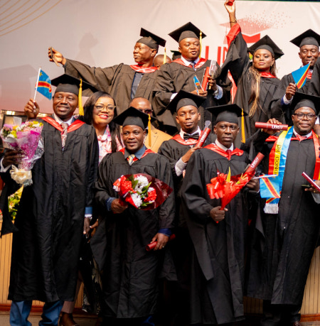 Happy graduates celebrate on stage wearing graduation gowns and caps