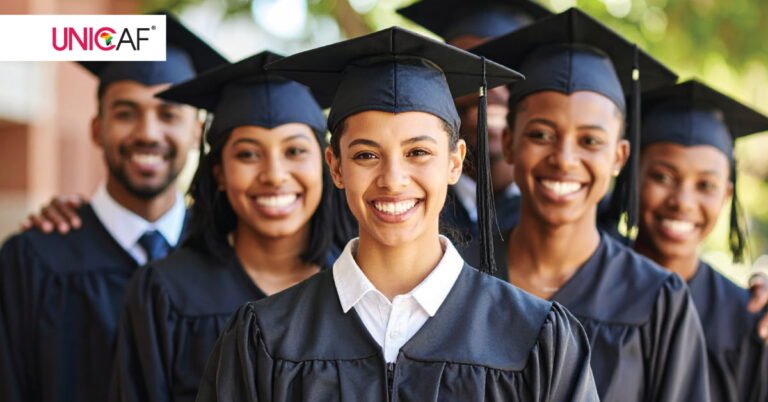 Smiling graduates wearing graduation gowns and caps.